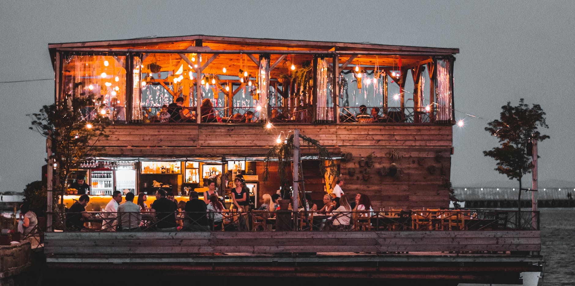 Goście jedzą kolację w przytulnej restauracji nad wodą wieczorem