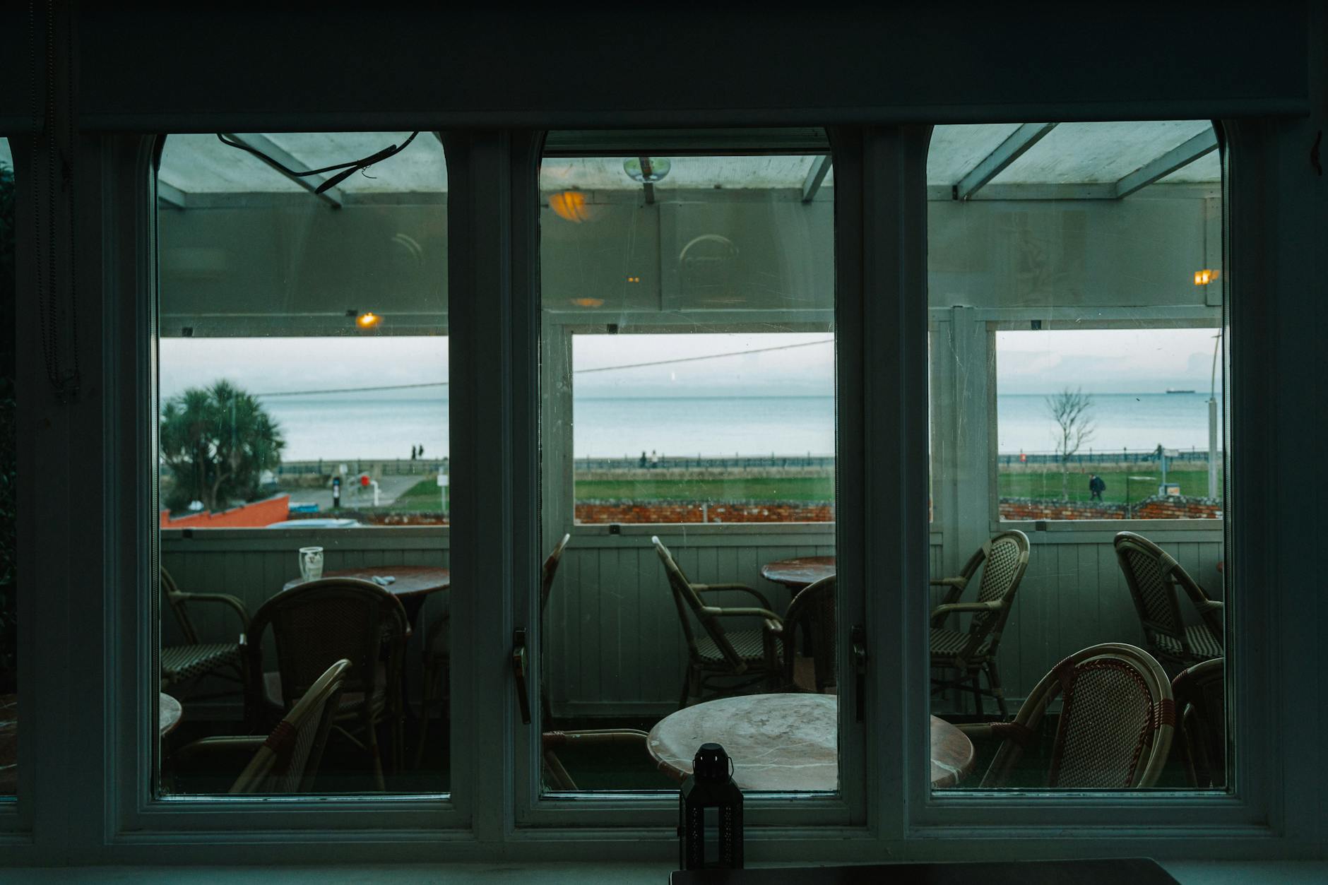 Puste kawiarniane stoliki z widokiem na spokojne morze poza sezonem