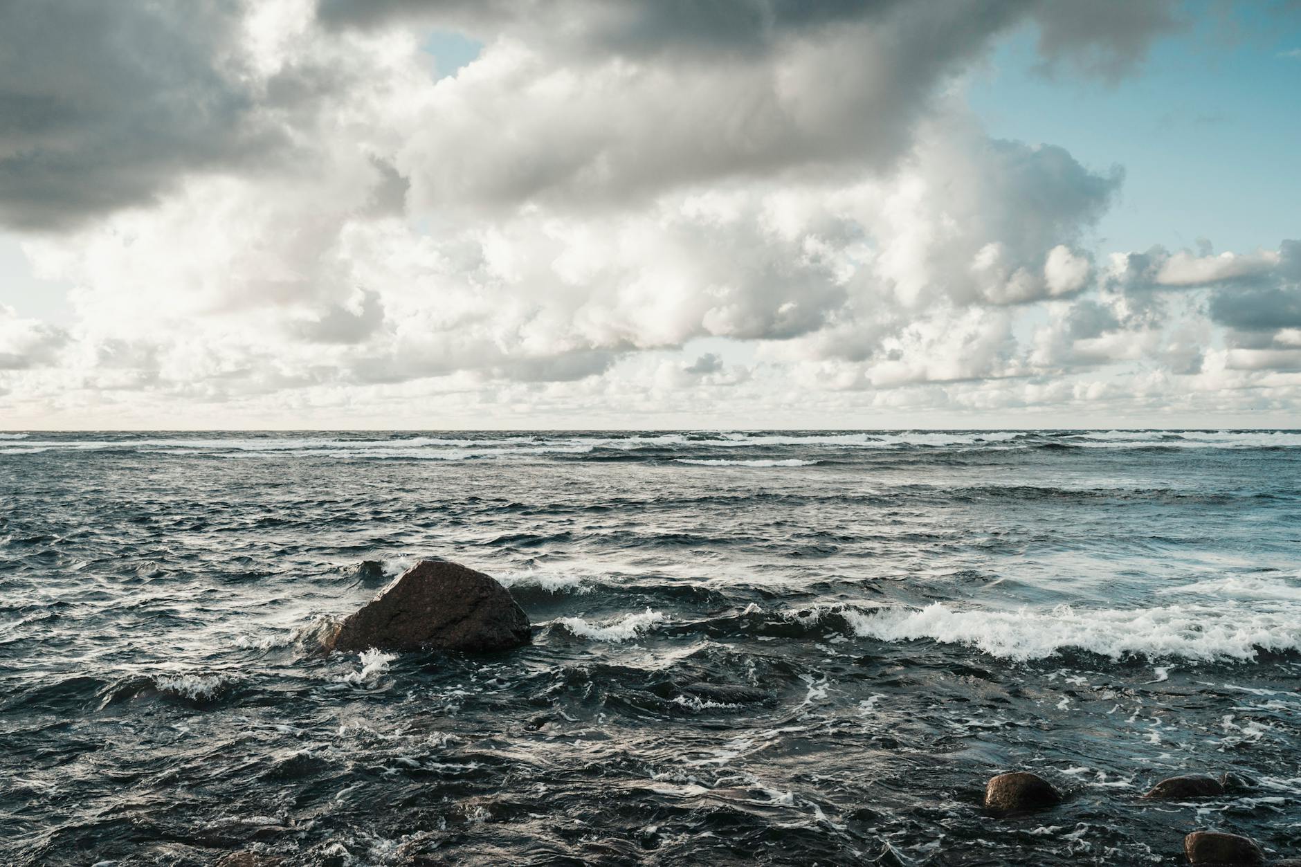 Skaliste wybrzeże Bałtyku przy wzburzonym morzu i ciężkich chmurach