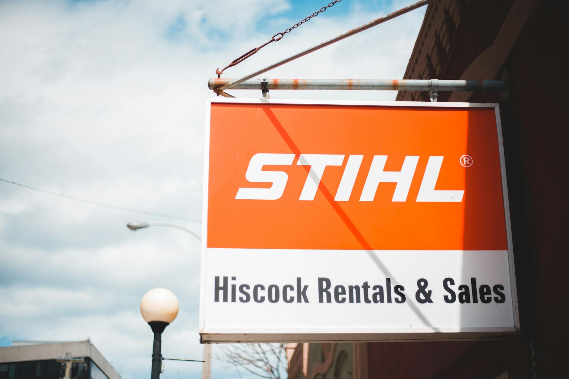 Szyld STIHL na tle miejskiej zabudowy i błękitnego nieba