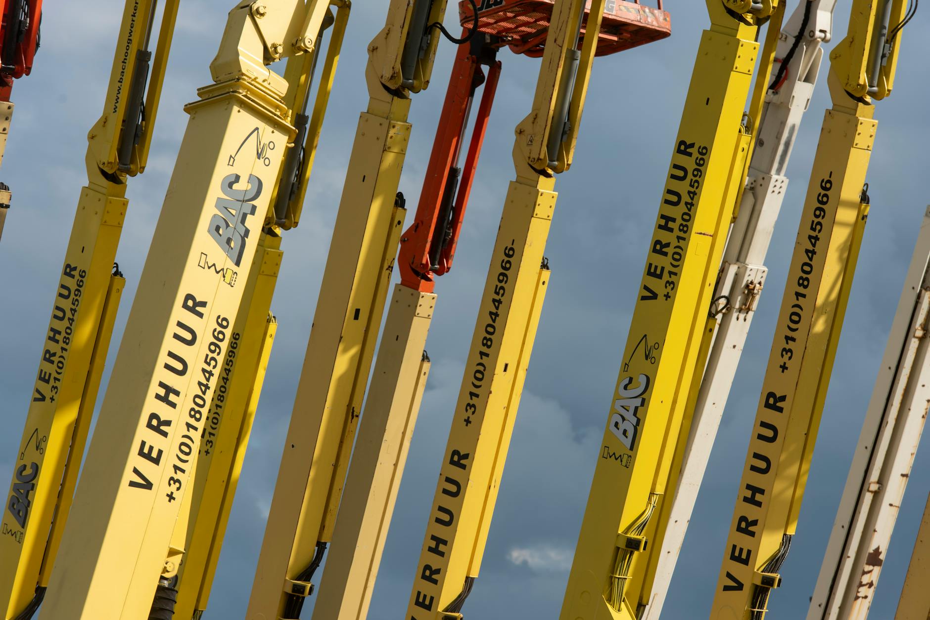 Żółte podnośniki koszowe z numerami na tle niebieskiego nieba Żółte podnośniki koszowe z numerami na tle niebieskiego nieba