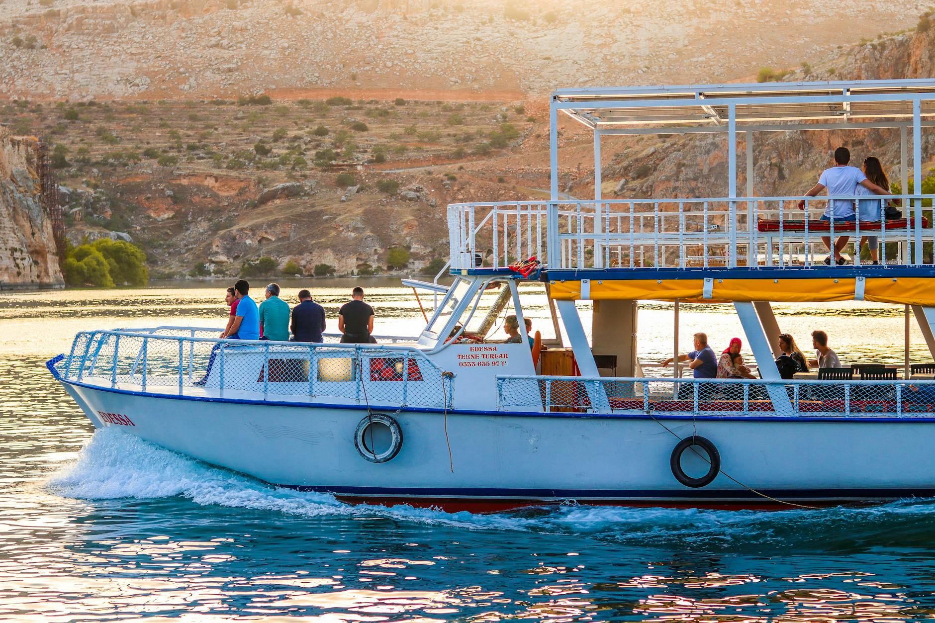 Statek wycieczkowy z pasażerami płynie po rzece między skalistymi wzgórzami