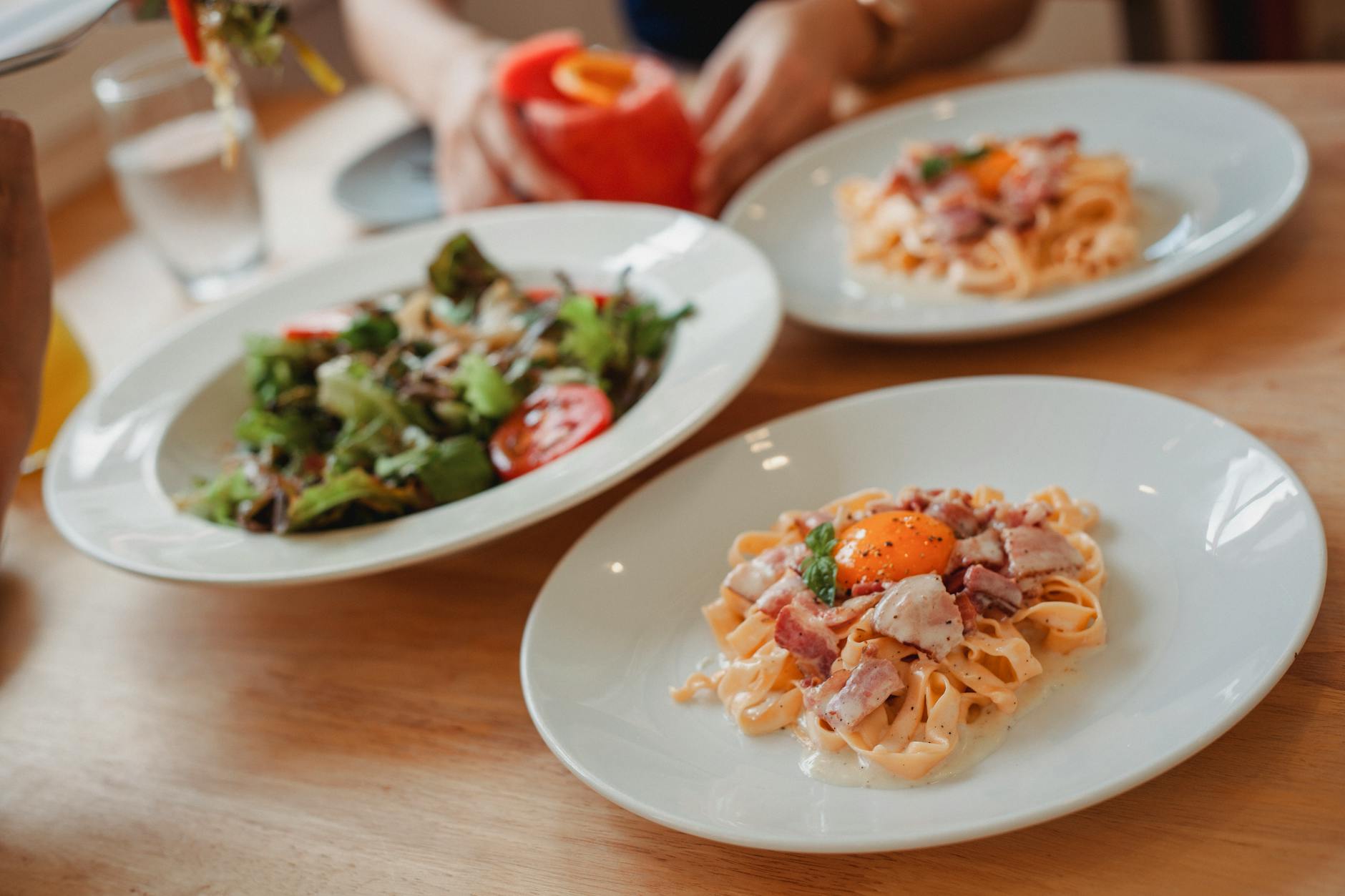 Talerze ze spaghetti i miska sałatki na drewnianym stole w restauracji