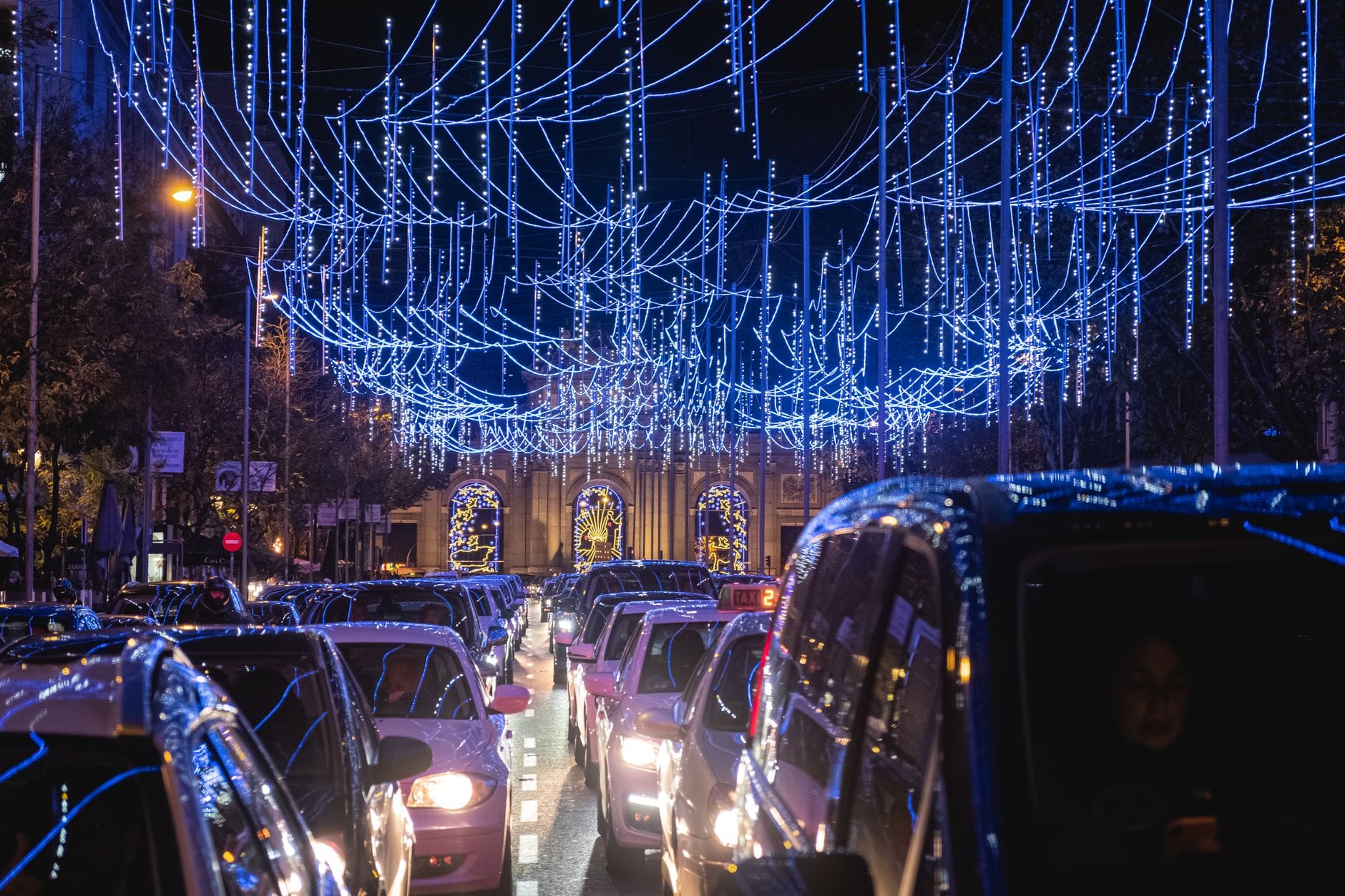 Nocny korek uliczny w mieście z niebieskimi, świątecznymi iluminacjami