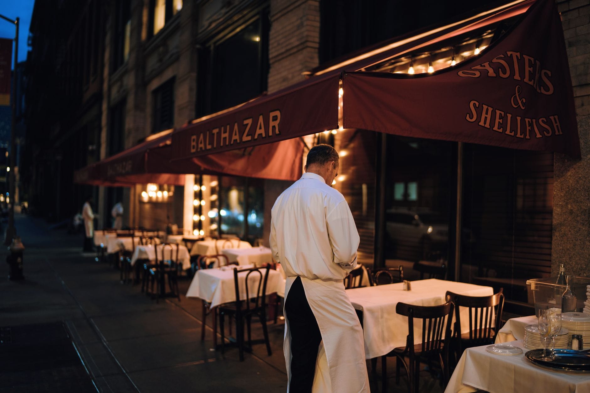 Elegancki ogródek restauracyjny nocą z obsługą szykującą stoły